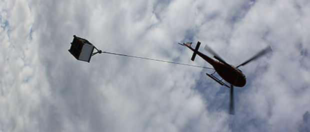 Helikopter i lufta med ventilasjonsaggregat. Foto: Caverion Norge